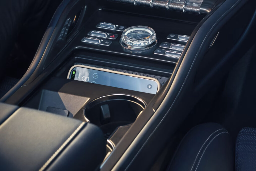 Car center console with smartphone, control buttons, and cup holder.