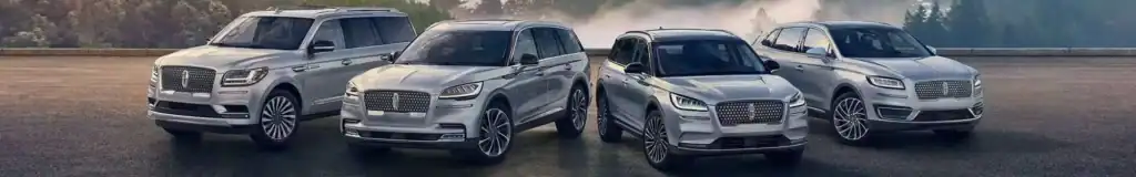 Three silver SUVs are parked in a row with a scenic forest background.