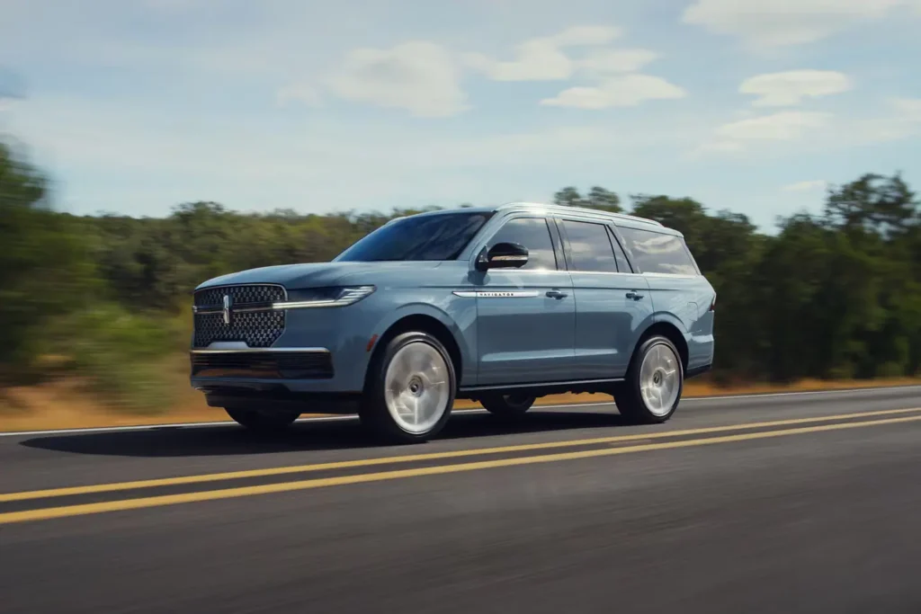 Blue SUV driving on a highway, surrounded by greenery, under a clear sky.