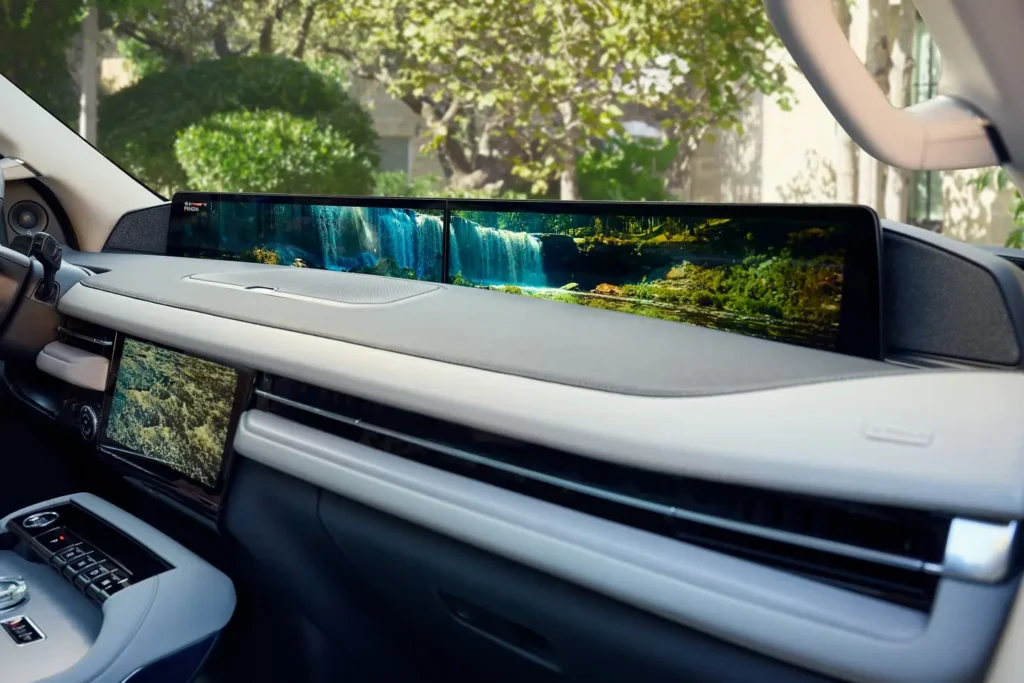 Car dashboard with digital display showing a waterfall scene, surrounded by lush greenery.